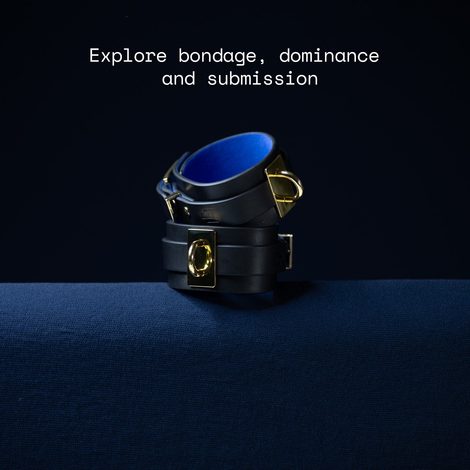 Black and gold leather wrist cuffs with blue interior on a dark background, text 'Explore bondage, dominance and submission' above.